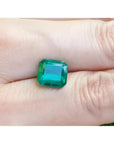 GIA certified 3.55 ct. emerald-cut Colombian emerald gemstone on a hand.