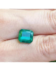 GIA certified 3.55 ct. emerald-cut Colombian emerald gemstone on a hand.