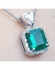 A natural certified emerald pendant with gold chain on a light background