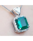 A natural certified emerald pendant with gold chain on a light background
