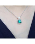Emerald green gemstone necklace on a person wearing a dark blue top.