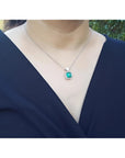 Colombian emerald pendant in 18K white gold, worn on a woman's neck.