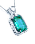 This GIA certified colombian emerald in this pendant is surrounded by a halo diamond, on the top bail a trillion-cut diamond.