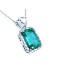 This GIA certified colombian emerald in this pendant is surrounded by a halo diamond, on the top bail a trillion-cut diamond.