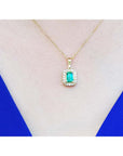 0.75 ct. GIA certified F1 Colombian emerald pendant with diamond halo in 18k yellow gold on a woman's neck.