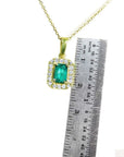 0.75 ct. GIA certified F1 Colombian emerald pendant in 18k yellow gold with diamond halo, next to a ruler.