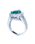 18K white gold ring with a large pear-shaped emerald surrounded by sparkling diamonds.