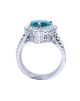 18K white gold ring with a pear-shaped deep bluish-green emerald surrounded by natural diamonds.