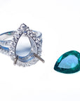 A 18k white gold mounting ring with a pear cut loose emerald aside.