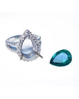 18K white gold ring setting with diamond halo next to a loose 4.02 ct pear-shaped deep bluish-green emerald.