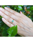 Minimalist 14K yellow gold ring with a petite, square-cut natural Colombian emerald on a hand.