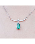 14k white gold necklace natural Colombian emerald dangling from a wavy central bar with diamonds pave set