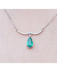 14k white gold necklace natural Colombian emerald dangling from a wavy central bar with diamonds pave set