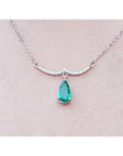 14K white gold necklace with a pear-shaped emerald dangling from a wavy diamond bar.