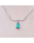 14K white gold necklace with a pear-shaped emerald dangling from a wavy diamond bar.