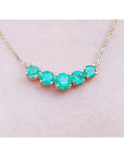 14K gold necklace with five round, medium green Colombian emeralds in elegant basket settings.