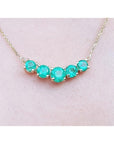 14K gold necklace with five round, medium green Colombian emeralds in elegant basket settings.