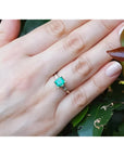Emerald ring with baguette side diamonds on a hand, crafted in 14K yellow gold.