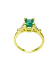 14K yellow gold ring with a vibrant emerald center stone and baguette side diamonds.