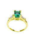 14K yellow gold ring with a vibrant emerald-cut emerald and baguette side diamonds.