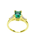 14K yellow gold ring with a vibrant emerald-cut emerald and baguette side diamonds.