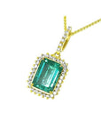 Emerald-cut emerald pendant with halo diamonds in 18K gold, featuring a brilliant green emerald.