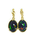 Pair of gold earrings with black opal stones on a topside view