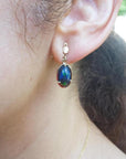 Ethiopian Welo black opal earrings with bluish-green and red-orange colors, set in 14K yellow gold.