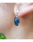 Ethiopian Welo black opal earrings with bluish-green and red-orange colors, set in 14K yellow gold.