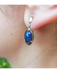 Ethiopian Welo black opal earrings with bluish-green and red-orange colors, set in 14K yellow gold.