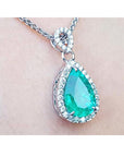 14k white gold pendant with a natural colombian emerald surrounded in a halo of genuine diamonds.