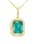 A natural emerald-cut colombian emerald surrounded by a halo diamond pendant in yellow gold.