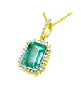 Emerald-cut emerald pendant with halo diamonds in 18K yellow gold, featuring a diamond-set bail.