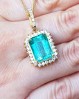Gold pendant with a natural colombian emerald held in a hand.