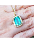 Gold pendant with a natural colombian emerald held in a hand.