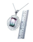 Emerald cut watermelon tourmaline pendant with diamonds on a 14K white gold chain, next to a ruler.