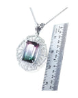 Emerald cut watermelon tourmaline pendant with diamonds on a 14K white gold chain, next to a ruler.