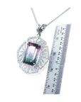 Emerald cut watermelon tourmaline pendant with diamonds on a 14K white gold chain, next to a ruler.