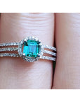 Emerald engagement ring with halo diamonds and three rows of diamonds on a 14K white gold band.