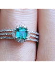 Emerald engagement ring with halo diamonds and three rows of diamonds on a 14K white gold band.