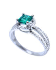 Emerald engagement ring with halo diamonds and three rows of diamonds on a 14K white gold band.