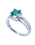 Emerald engagement ring with halo diamonds and three rows of diamonds on a 14K white gold band.