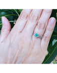 Emerald engagement ring with halo diamonds on a 14K white gold band, worn on a hand.