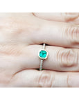 14K yellow gold ring with a medium green emerald in a tapered bezel, flanked by natural diamonds.