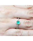 14K yellow gold ring with a medium green emerald in a tapered bezel, flanked by natural diamonds.