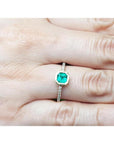14K yellow gold ring with a medium green emerald in a tapered bezel, flanked by natural diamonds.
