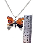 Sterling silver agate butterfly pendant necklace with orange, brown, and black wings, shown with a ruler.