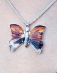 Butterfly-shaped agate pendant on a chain against a skin background