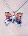 Butterfly-shaped agate pendant on a chain against a skin background