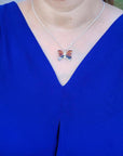 Sterling silver agate butterfly pendant necklace with orange, brown, and black hues, worn on a blue top.
